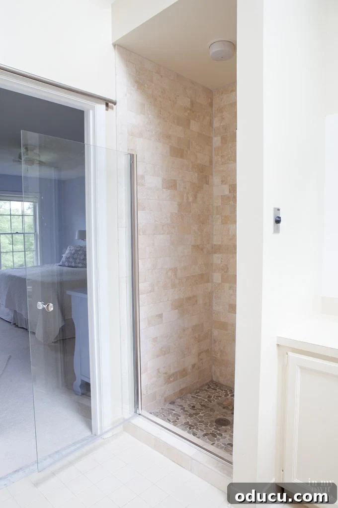 Luxury Master Shower Transformation 17 Master bathroom decorating ideas, featuring the completed tumbled stone tile shower makeover with the glass shower door wide open, revealing a spacious and elegant design.