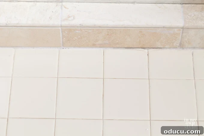 Luxury Master Shower Transformation 6 New stone tile shower floor featuring grey pebble mosaics, neatly transitioning to the existing beige ceramic tile on the main bathroom floor.