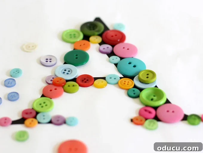 Create Custom Button Letter Wall Art 8 Overhead view of various buttons being laid out on a printed letter template on a table, before gluing.