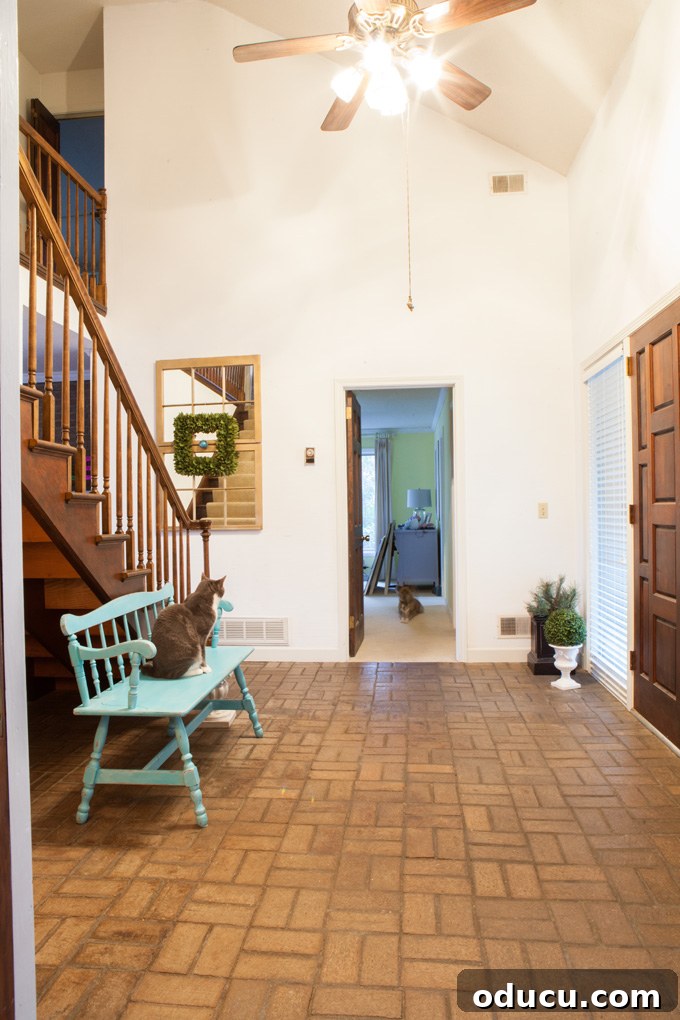 A Glimpse Inside My Brand New Home 3 View of the two-story foyer from the kitchen hallway, showcasing brick flooring and distant rooms.