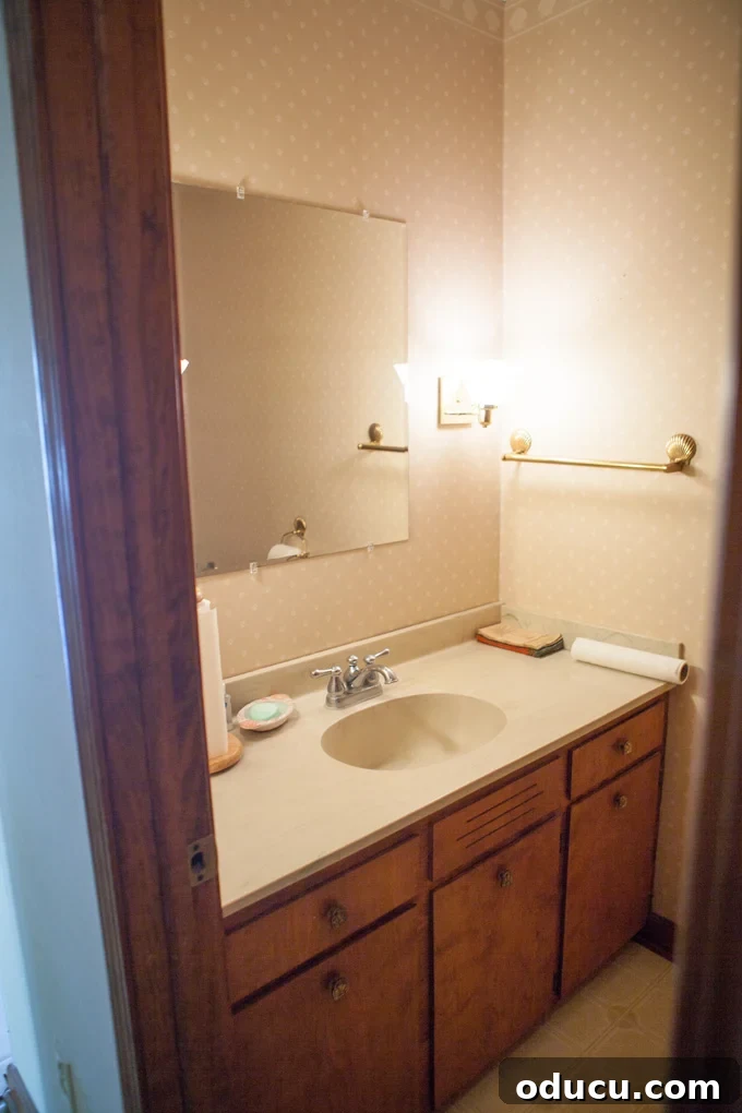 A Glimpse Inside My Brand New Home 23 Interior view of a powder room with patterned wallpaper and dated fixtures.
