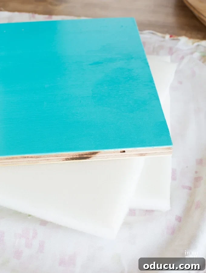 How to staple gun fabric to a storage crate cushion, showing fabric, foam, and plywood layers