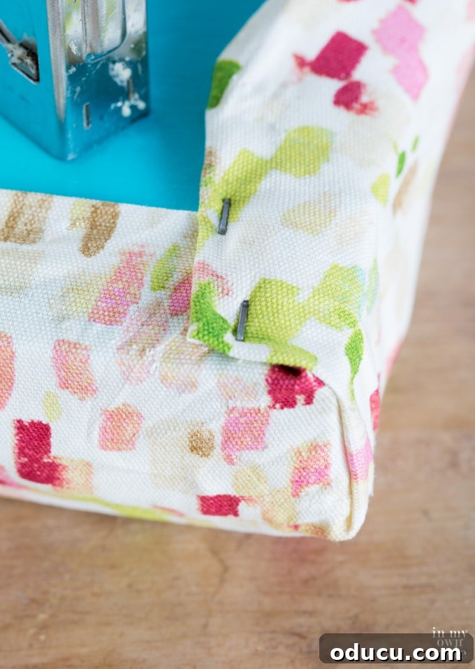 dorm room decor DIY using storage crates, showing fabric being wrapped and stapled