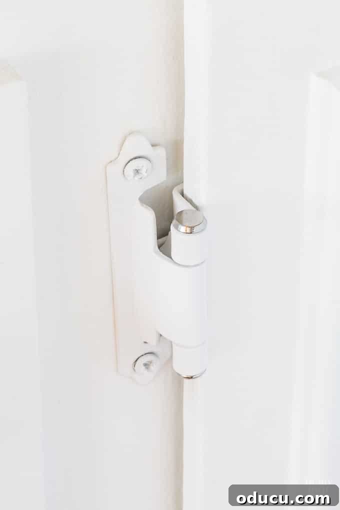 Newly installed white kitchen cabinet hinges with subtle chrome accents, perfectly matching the updated hardware.