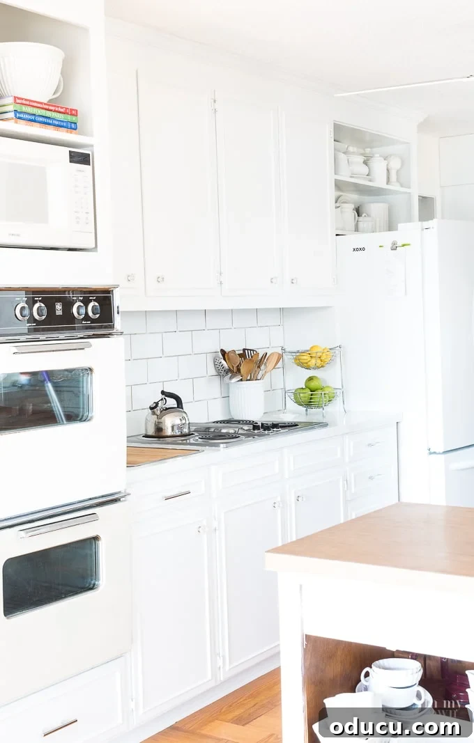 Overview of an updated kitchen side, showing newly installed cabinet hardware, awaiting backsplash grout.