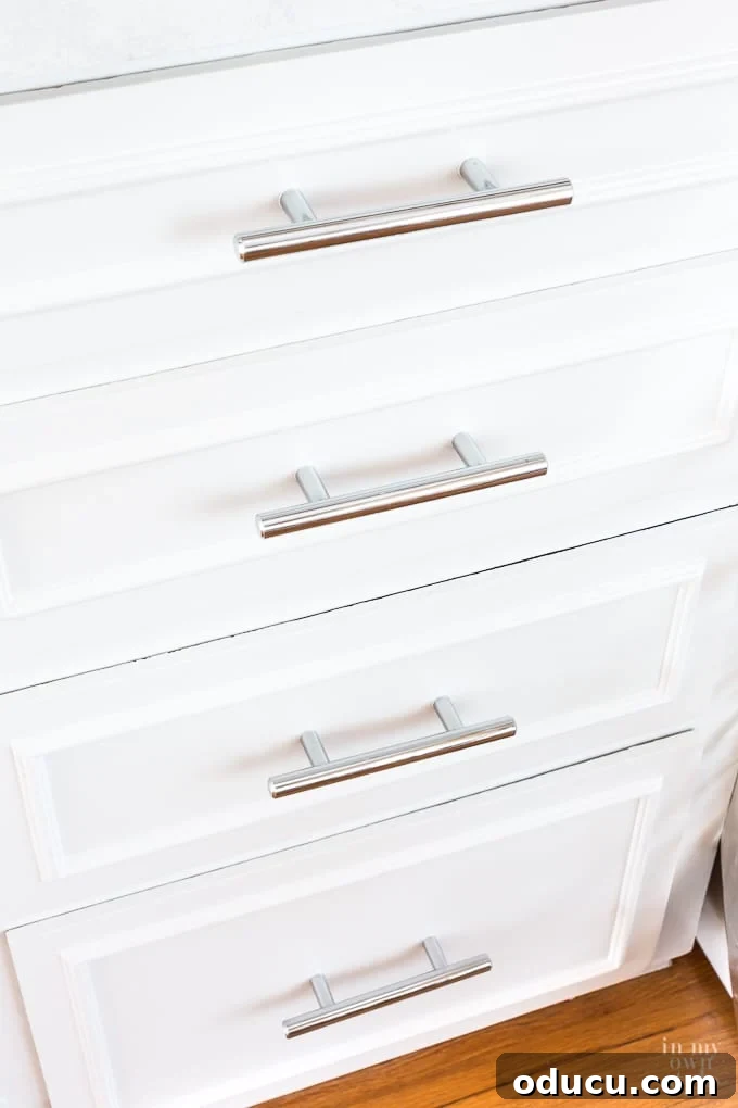 Transformed kitchen cabinets with new paint and modern chrome hardware, showing a significant update.