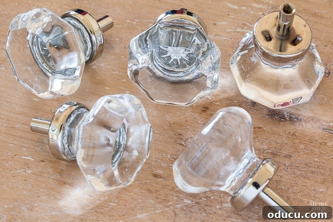 Close-up of new octagon glass cut cabinet knobs with chrome accents on a white cabinet.
