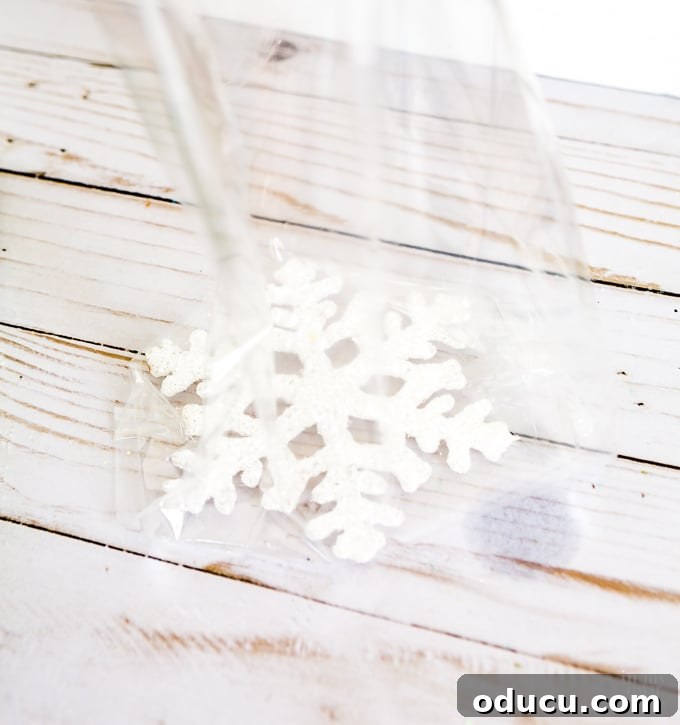 Vibrant Fragrant Holiday Pinecone Creations 16 Step-by-step guide on how to wrap small holiday items for gifting, starting with placing a snowflake ornament.