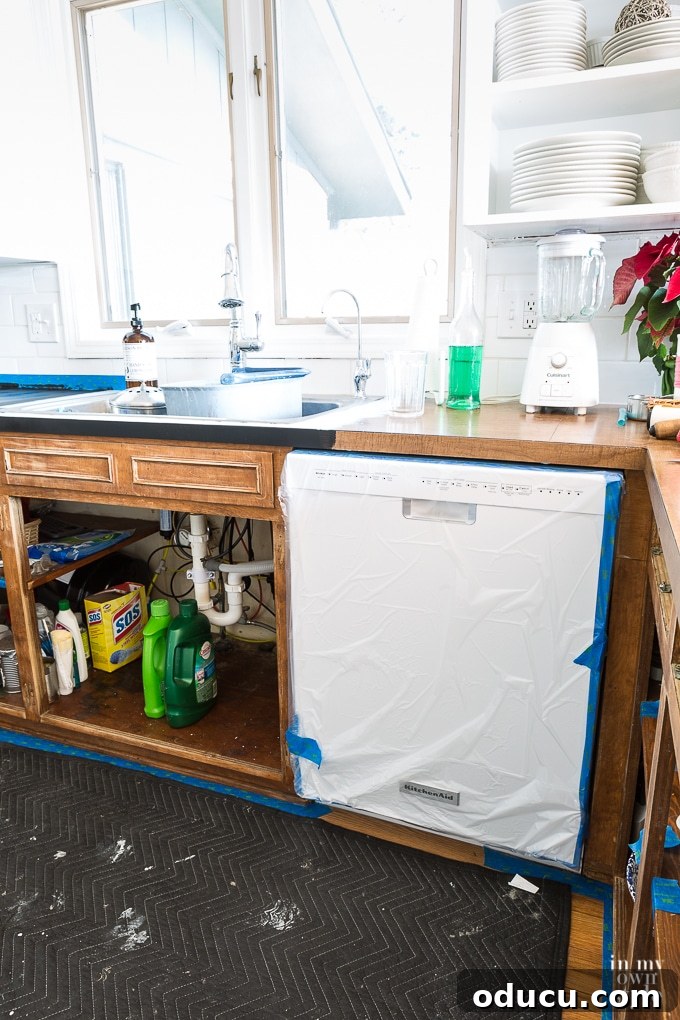 Kitchen Remodel: The Home Stretch 6 Protecting a new dishwasher with plastic sheeting and painter's tape during kitchen cabinet painting