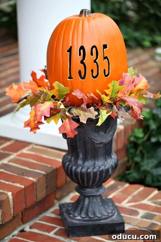 Transform an Old Urn into a Chic Side Table 3 Garden urn adorned with a pumpkin featuring a carved house address number, used as festive fall porch decor.