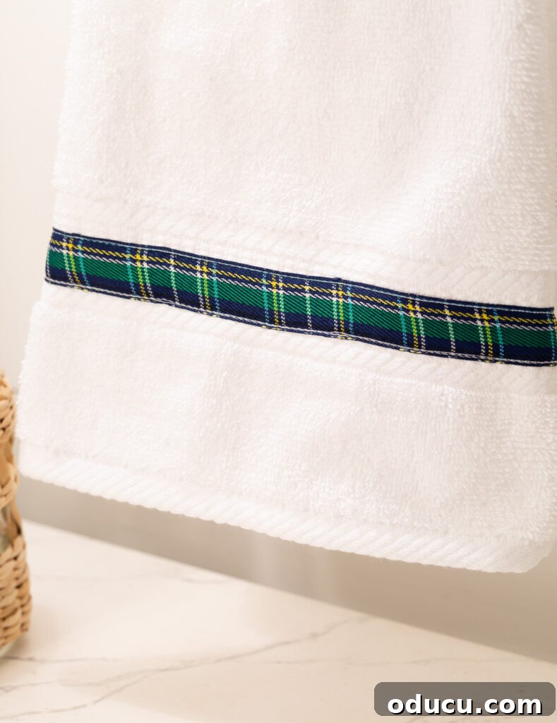 Elevate Your Bathroom With Towel Decor 19 A pristine white hand towel subtly enhanced with a beautiful blue plaid ribbon embellishment, showcasing a potential challenge with certain ribbon types.