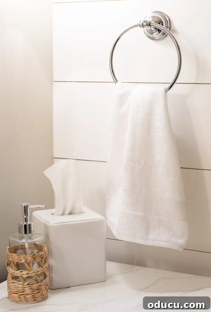 Elevate Your Bathroom With Towel Decor 3 A crisp white bath towel neatly folded and hanging on a modern towel ring in a bright, clean bathroom setting, ready for embellishment.