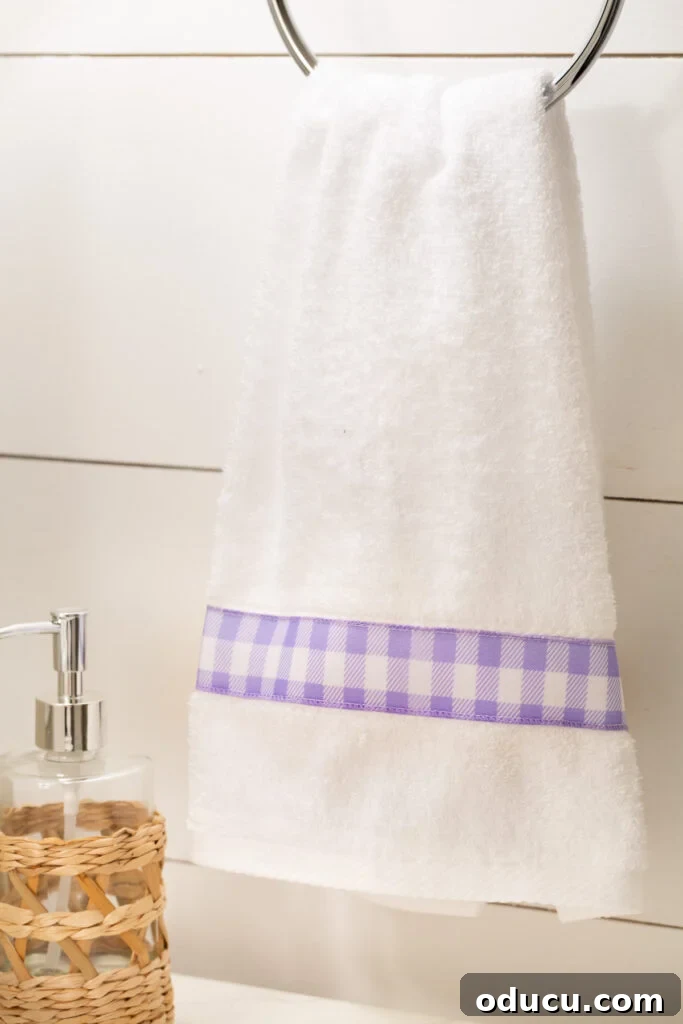 Elevate Your Bathroom With Towel Decor 7 A pristine white towel adorned with a charming lavender and white check ribbon trim, adding a touch of country chic to the bathroom.