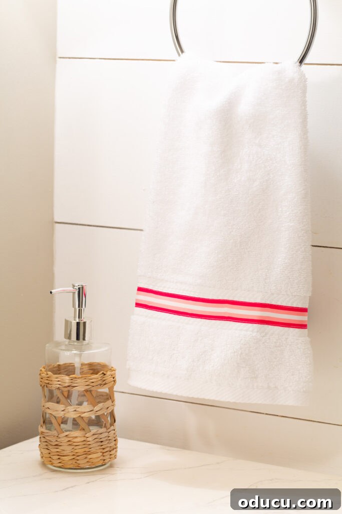 Elevate Your Bathroom With Towel Decor 8 Another close-up of a hand towel, featuring the same pink and white striped ribbon meticulously sewn on, highlighting consistency and style.