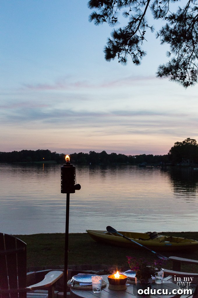 My Lakeside Haven 12 An Urban Metal Torch by TIKI strategically placed by the lakeside, casting a warm glow and enhancing the natural beauty of the water's edge.