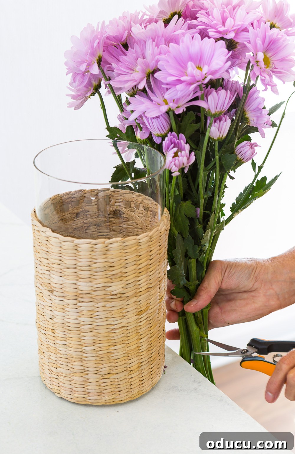 Beautiful Flower Arrangements Made Simple 3 Hands arranging a bouquet of single-color flowers in a glass vase, demonstrating the simple method.