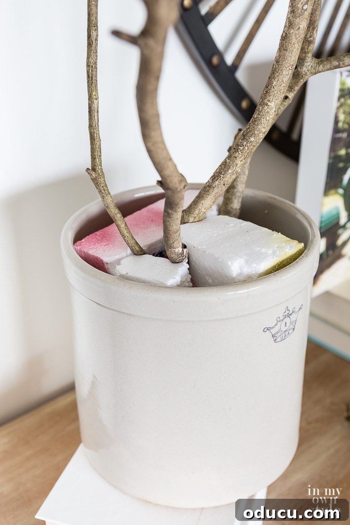 Effortless Autumn Centerpiece 5 Materials laid out for an easy DIY autumn floral arrangement, including a ceramic crock, branches, and faux fall foliage
