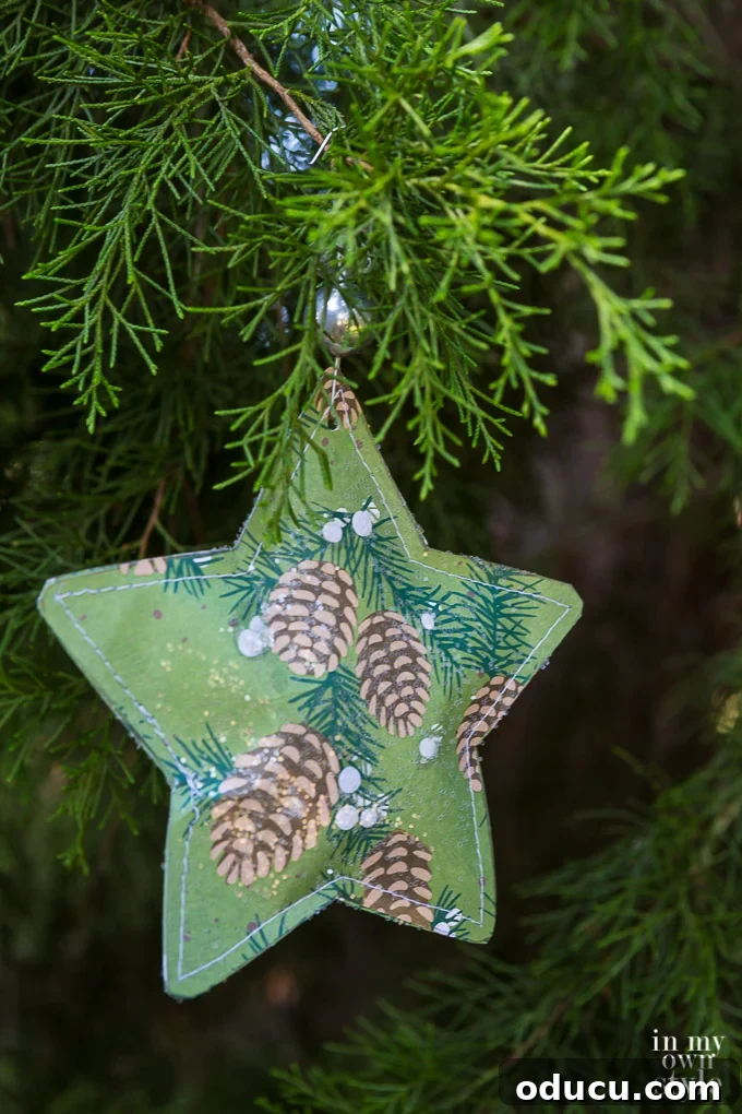 Hidden Treasure Star Ornament for Christmas 23 Scrapbook paper star ornament with silver bead hanging from Christmas tree.