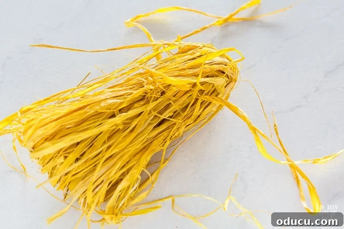 Craft Your Own Tassels: Elevate Your Home Decor 12 Yellow raffia being made into a fall decorating tassel