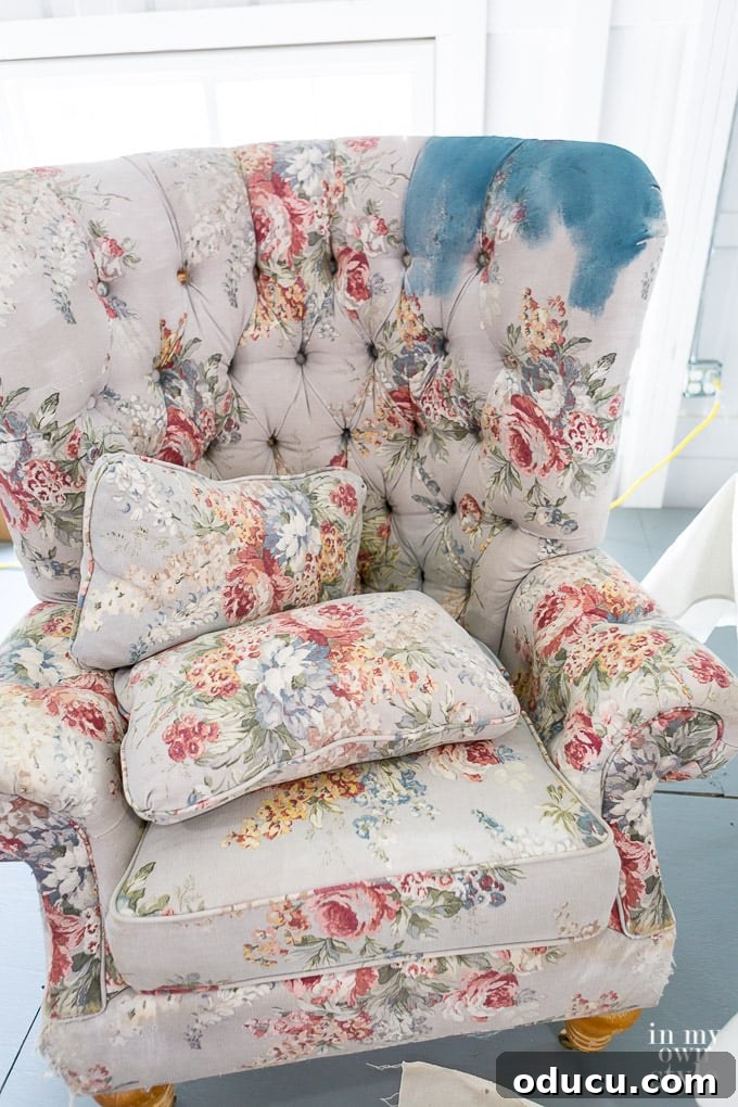 A wing chair being painted with Annie Sloan Chalk Paint, showcasing the simple tools needed for upholstery transformation.