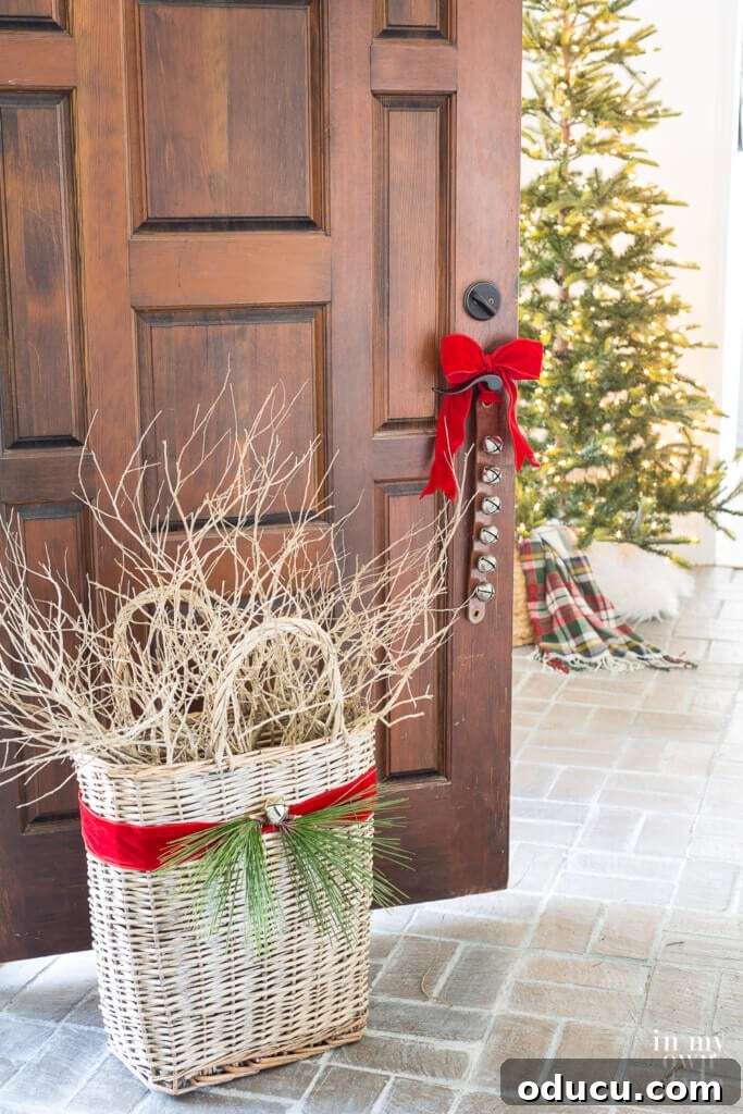 Red ribbon around large basket filled with branches. Christmas tree in distance.