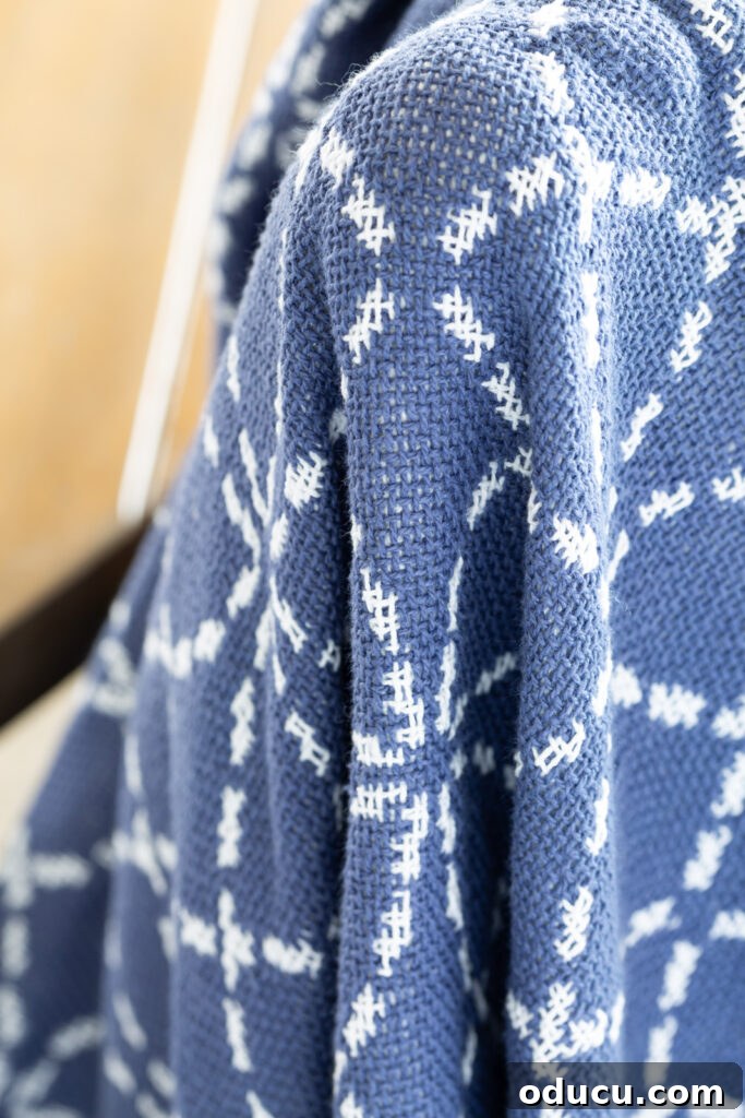 Close up of a blue and white cotton throw blanket with intricate weaving.