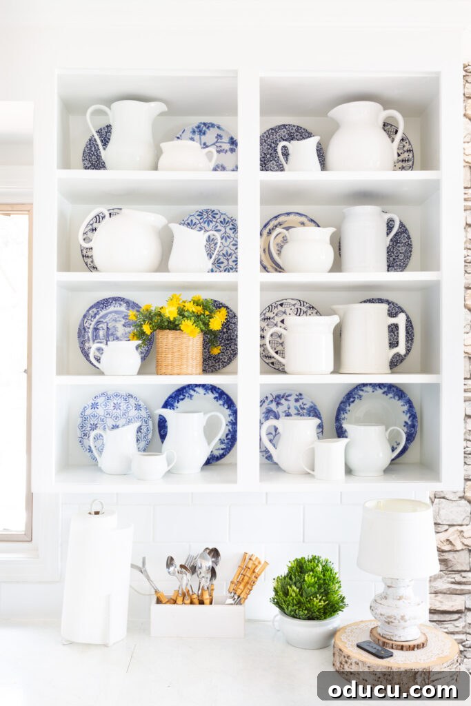 Blue and white decor accents on open shelves in a white kitchen, featuring pitchers and plates.