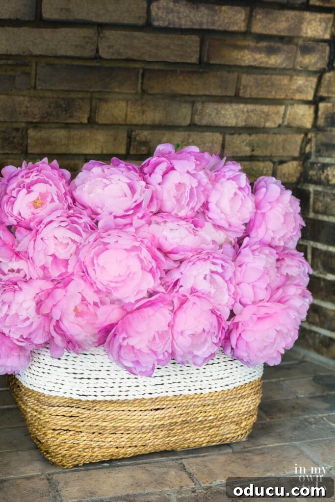 Mastering Faux Florals: Top 12 Decorating Secrets 11 A large white and natural color basket in empty fireplace filled with pink peonies.