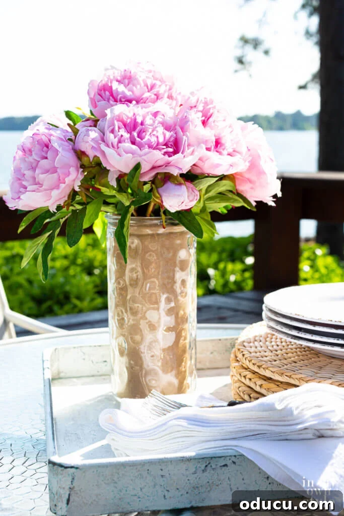 Mastering Faux Florals: Top 12 Decorating Secrets 12 Tall glass vase on deck by lake changed to be a colorful glass vase to hold flowers.