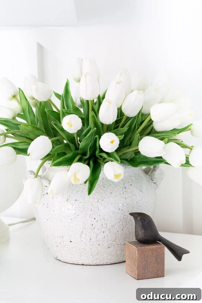 Mastering Faux Florals: Top 12 Decorating Secrets 3 White tulips in white crackle finish cachepot. Black bird on wood cube. Both on a foyer console table.