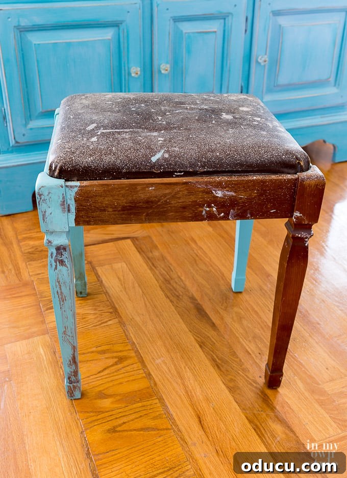 From Neglected Stool to Elegant Ottoman 2 Old sewing machine square stool before makeover, awaiting its transformation.