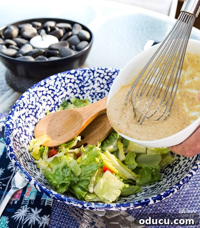 The Ultimate Anchovy-Free Caesar Salad 11 Whisking dressing over lettuce in big bowl.