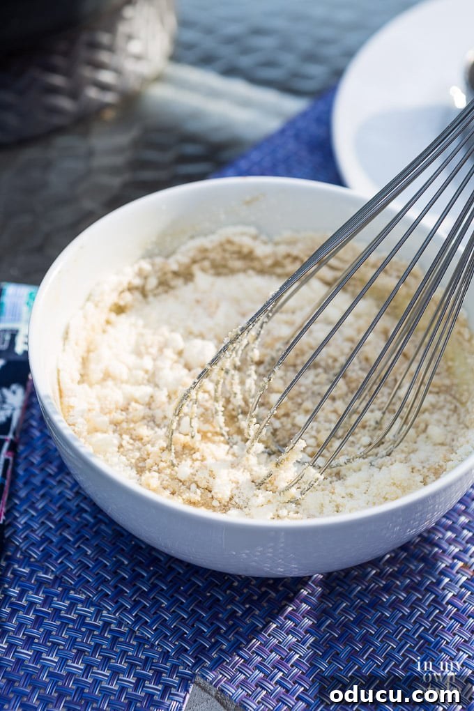 The Ultimate Anchovy-Free Caesar Salad 7 Whisking cheese into dressing that is in a white bowl.