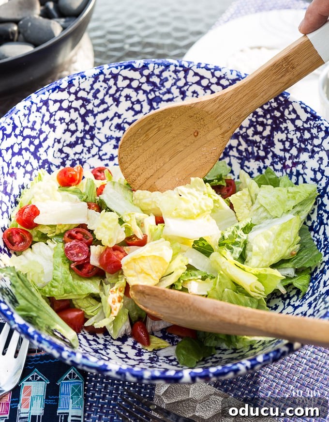 The Ultimate Anchovy-Free Caesar Salad 10 Mixing salad dressing into lettuce with a wooden spoon.