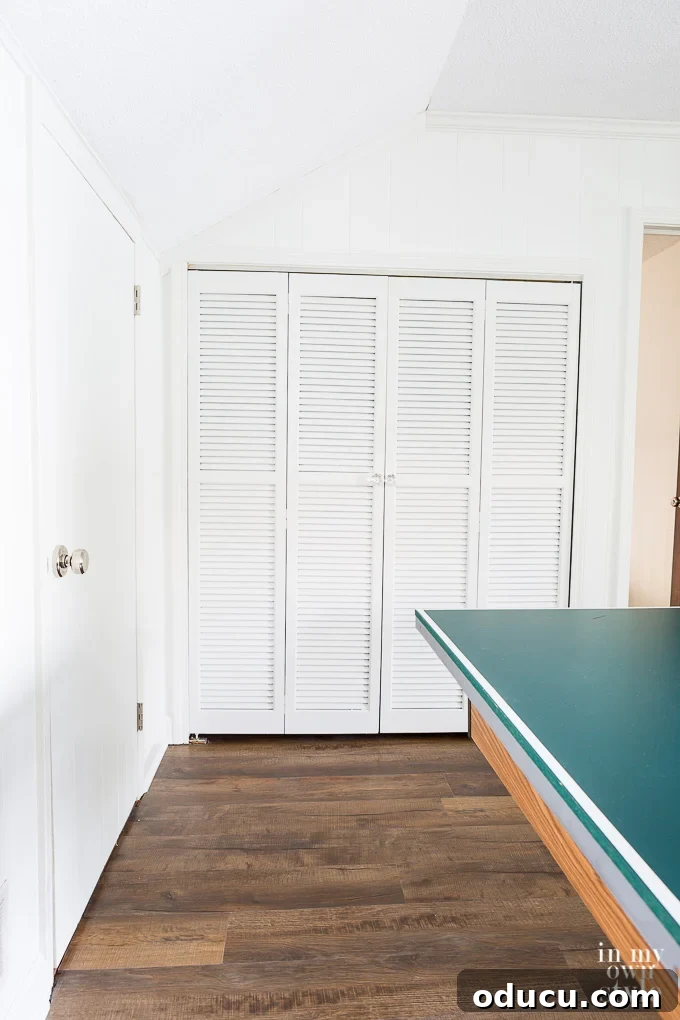 White painted louvered doors contrasting with dark LVP flooring
