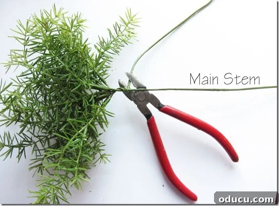 Craft Your Own Lifelike Topiary 11 Wrapping individual faux greenery stems around a main stem to form a cluster for the topiary.