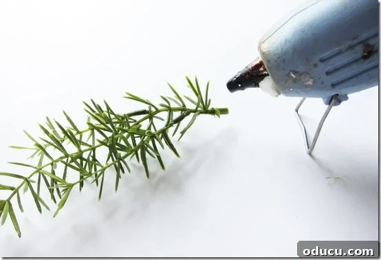 Craft Your Own Lifelike Topiary 15 Applying hot glue to greenery snippets to hide the topiary attachment point.