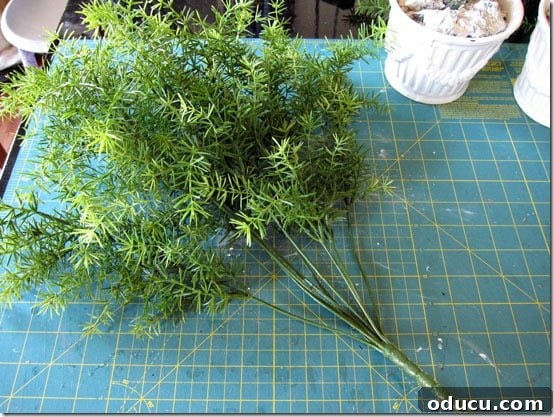 Craft Your Own Lifelike Topiary 5 Using wire cutters to separate individual faux greenery stems from the bouquet.
