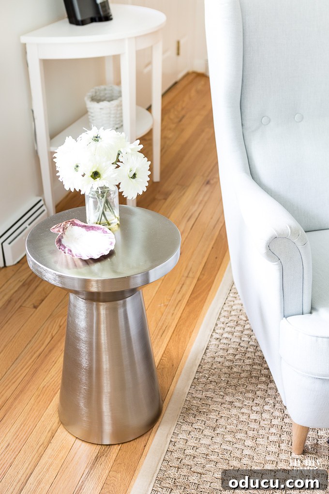 A modern silver side table from IKEA in a minimalist white living room, showcasing functional and aesthetic choices.
