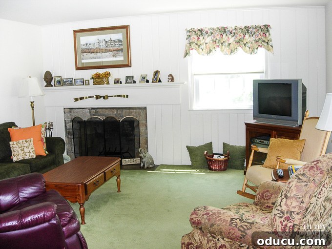 An older living room, cluttered with various items, awaiting a decluttering and decorating makeover.