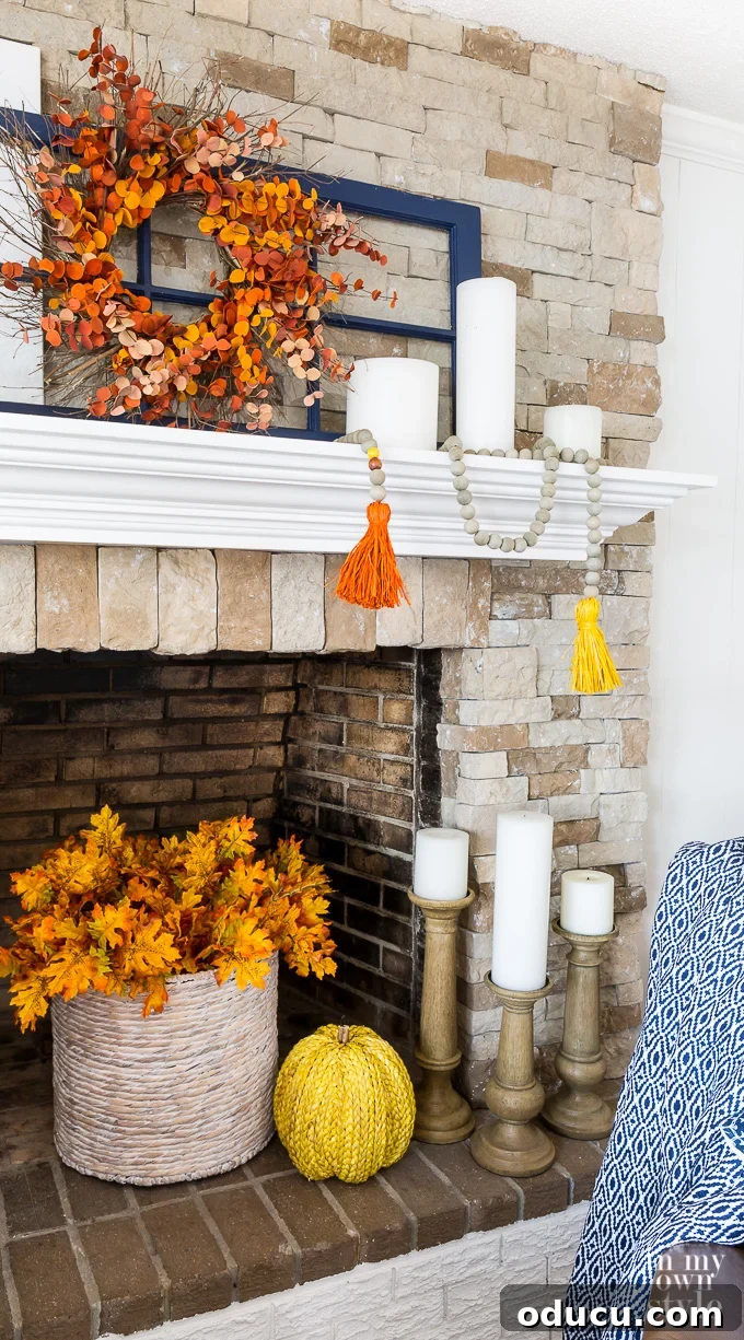 Autumn Home Decor: DIY Wood Bead Garland for Your Fall Mantel A cozy fall-decorated living room featuring a stone fireplace with a white mantel adorned with an autumn-inspired wood bead garland and other seasonal accents.