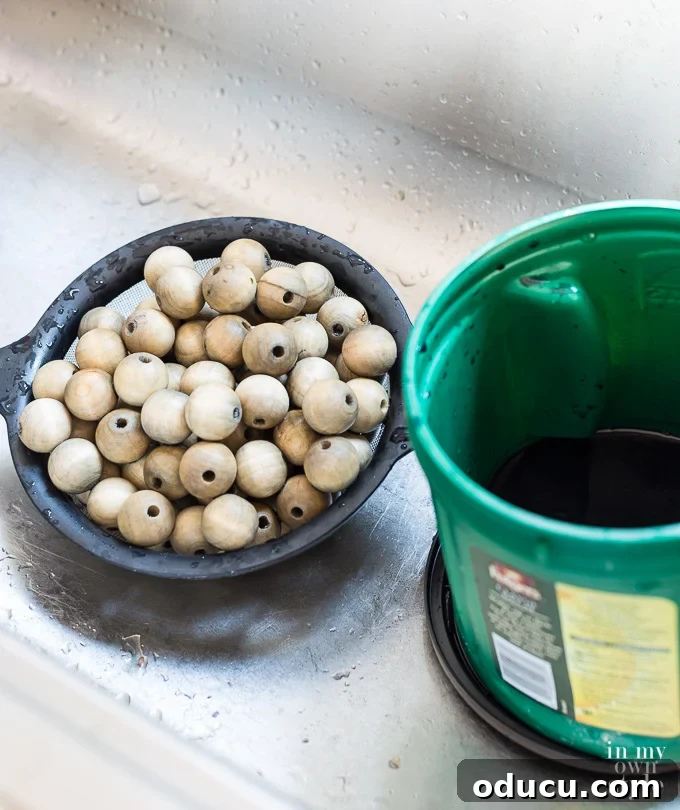 Staining Wood Beads for a Driftwood Finish: A DIY Tutorial Wood beads being stained with driftwood finish in a kitchen sink using a colander, showcasing the DIY staining process.