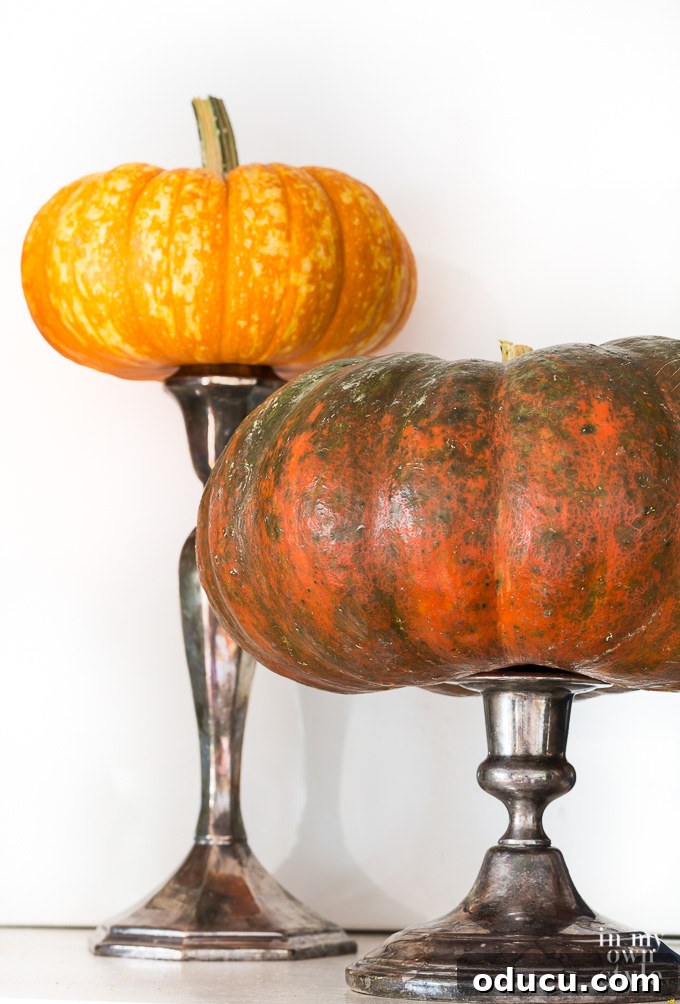 Clever Autumn decorating idea using candle holder and pumpkins. Pumpkins perched on candlestick along a fireplace mantel for fall