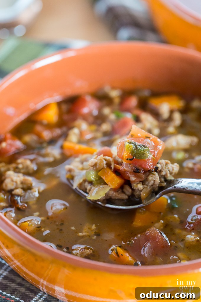 Sausage and lentil soup presented in a large orange bowl, ready to serve.