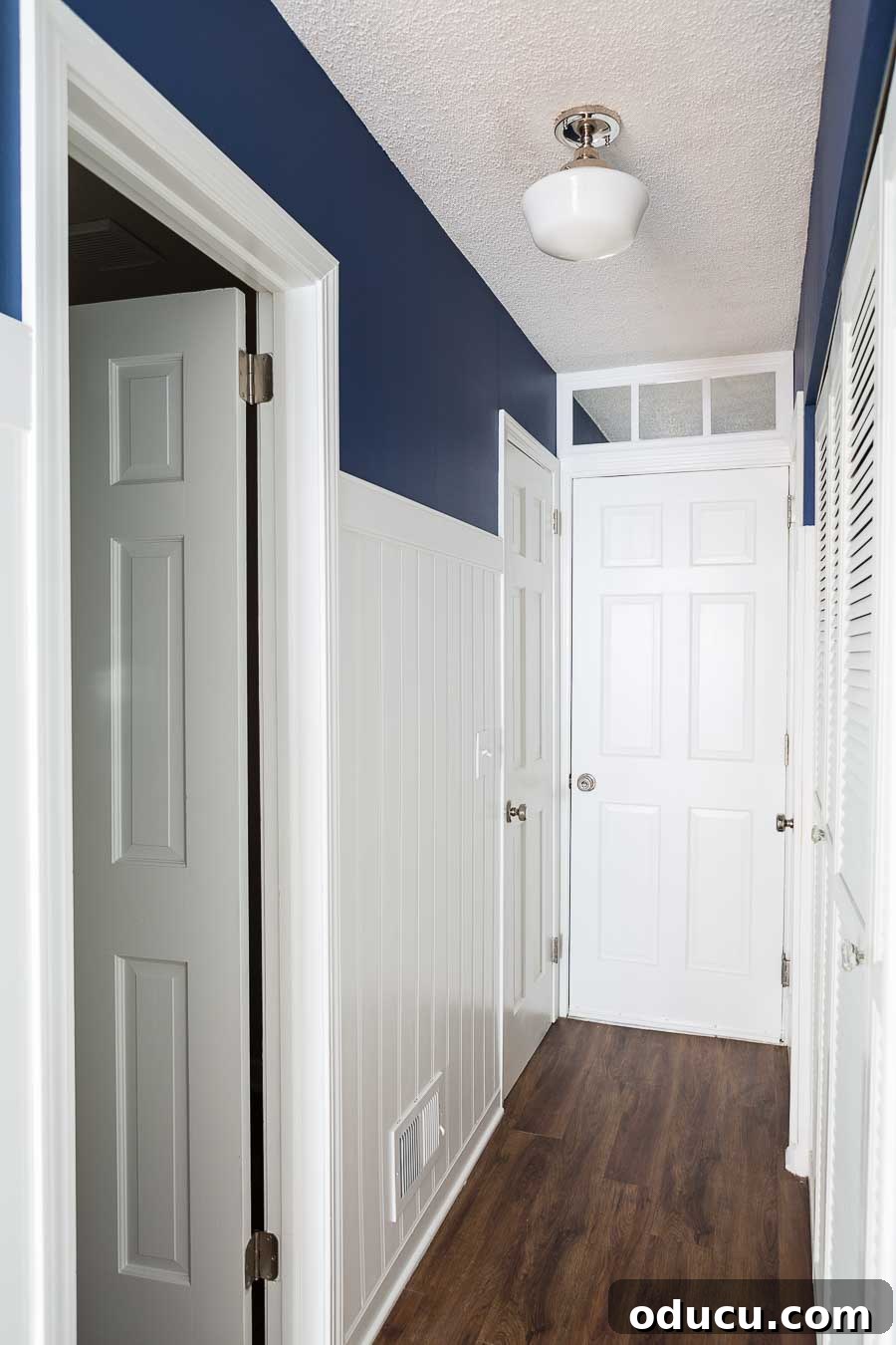What colors are best to use to paint walls in a dark room? A faux transom crafted from a mirror, strategically placed above a door to brighten a formerly dark hallway, reflecting ceiling light.