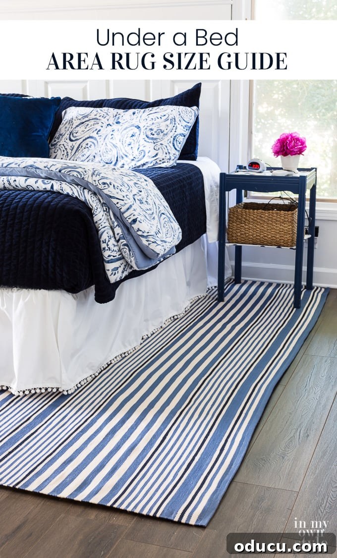 What size area rug should I put under my bed? Find out what to consider and check this guide to choose the right size for your decorating style and budget. Blue and white decorated bedroom with blue and white striped area rug under the bed.