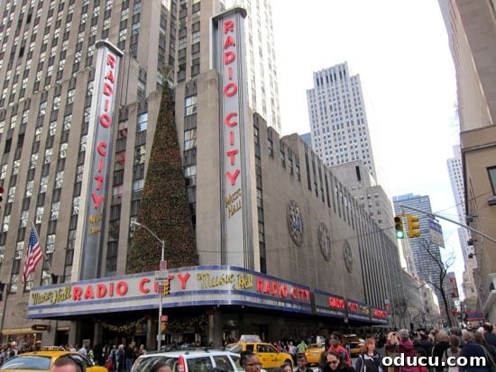 New York City at Christmas is a day trip must. A stunning photograph of Radio City in Manhattan adorned with Christmas decorations, highlighting the magical experience of New York City during the holidays.