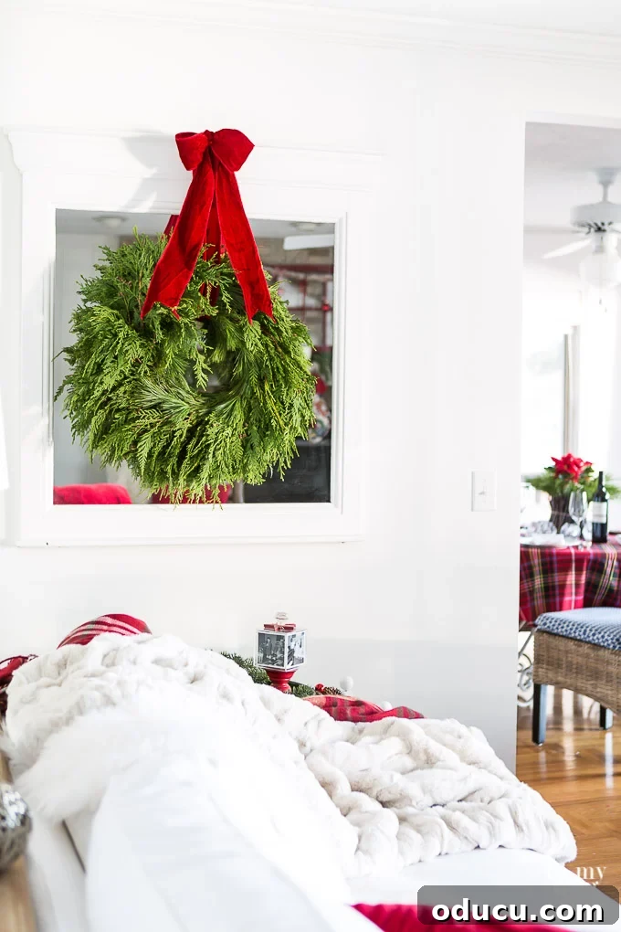 How to hang a real evergreen Christmas wreath simply on a mirror with ribbon. A beautifully simple display of a real evergreen Christmas wreath hung on a mirror with a elegant ribbon, demonstrating how to incorporate natural decor.