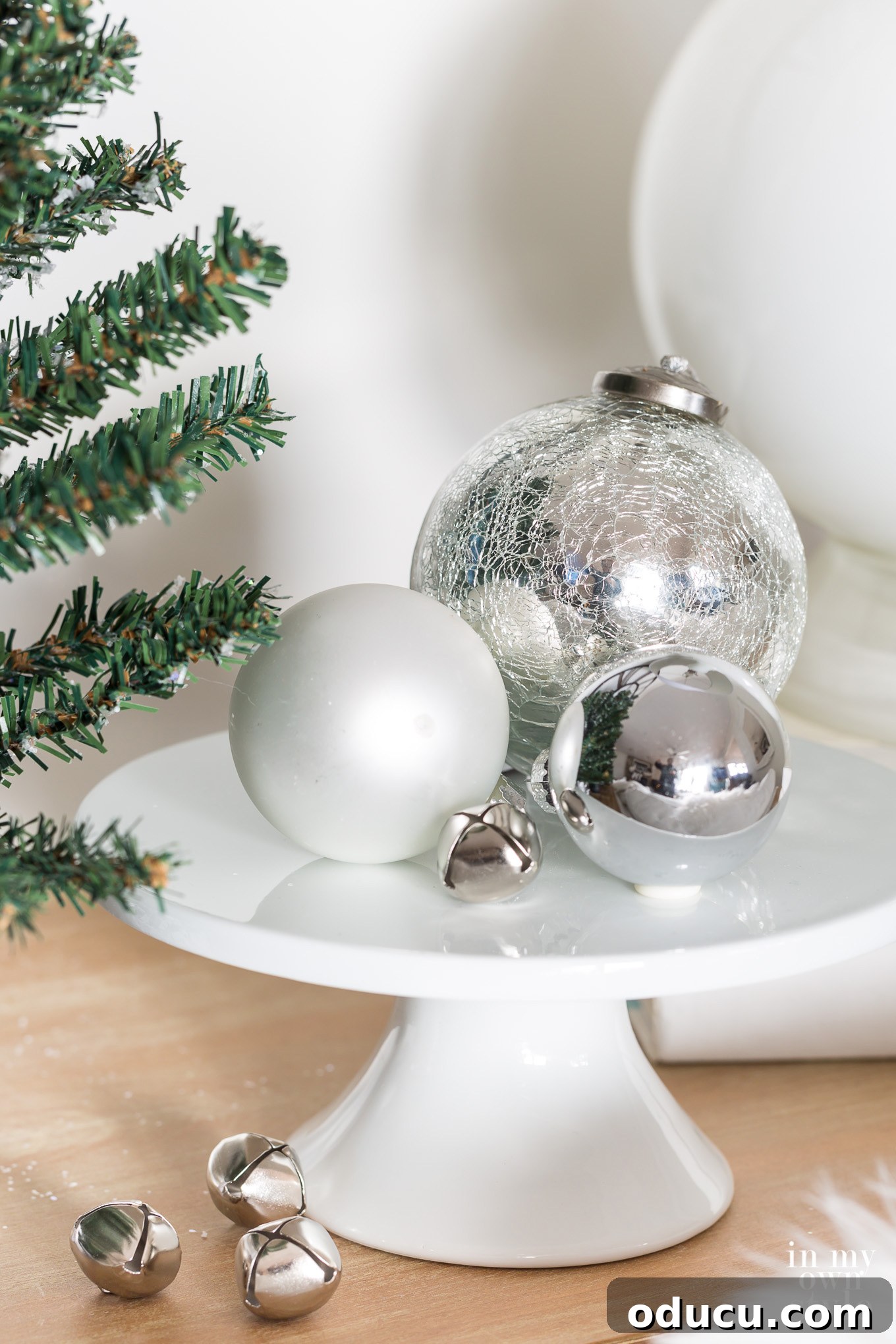 Shiny silver Christmas ornaments on white pedestal. Shiny silver Christmas ornaments on white pedestal, reflecting the festive glow