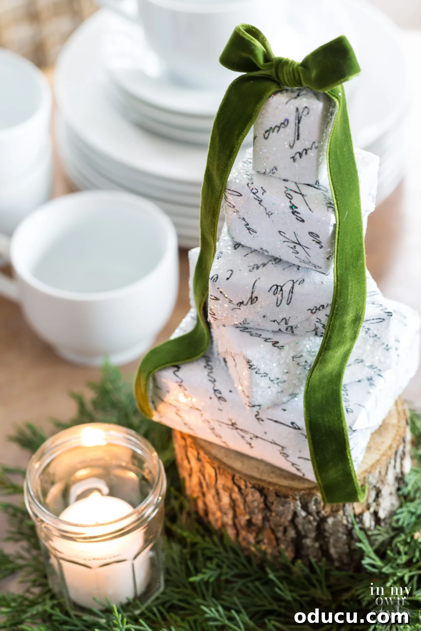 How to make a table top Christmas tree or centerpiece using boxes. #Christmasdecorating #Christmastable A stack of mini boxes wrapped in French Script paper with pretty green velvet bow, an elegant centerpiece